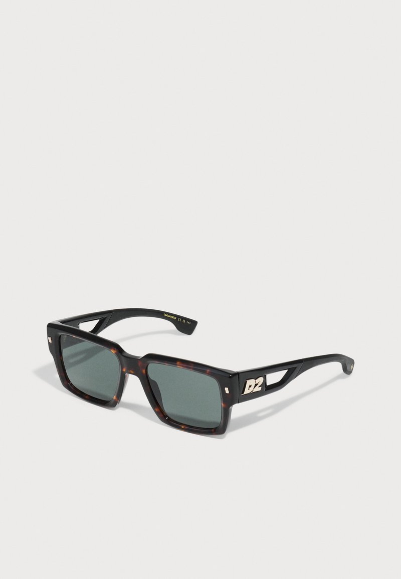 Black and tortoiseshell square sunglasses with green lenses and gold hardware detail on the arm, featuring a cutout design.