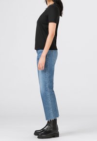 Svart kortärmad t-shirt med rund halsringning, tillsammans med ljusblå cropped jeans med fransade kanter och svarta ankelstövlar med tjock sula.