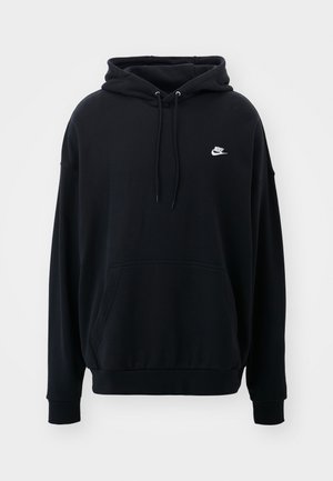 Svart hoodie i mjukt tyg, med en framficka, dragsko i huvan och en liten vit Nike-logga på bröstet.
