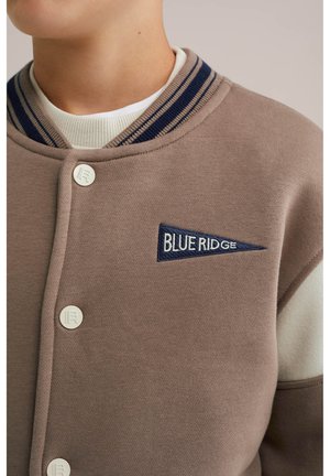 Brązowa bluza z raglanowymi rękawami, z granatowym ribbami i białymi akcentami. Guziki w kolorze kremowym, z haftowanym niebieskim logo "BLUE RIDGE".