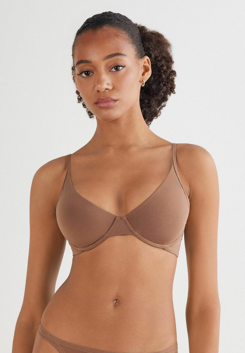 Hnědá podprsenka se hladkým povrchem, s kosticemi a širokými ramínky. Jednoduchý design s minimálně strukturovaným tvarem, ideální pro pohodlí.