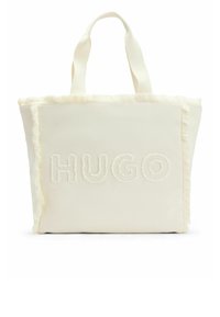 Borsa tote in tessuto crema con bordi sfrangiati, caratterizzata dal testo in rilievo "HUGO" sulla parte anteriore. Manici robusti per il trasporto.