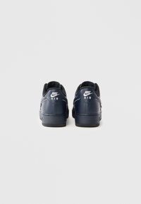 Baskets Nike Air bleu marine avec une finition en cuir lisse, un col rembourré et des accents de logo blanc sur le talon. Semelle en caoutchouc avec traction.