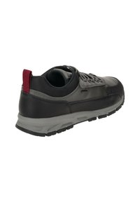 Schwarzer und grauer Sportschuh mit Obermaterial aus Leder und Textil, strukturiertem Gummisohle und einem roten Akzent an der Ferse.