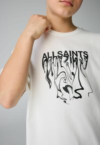 Biała bawełniana koszulka z krótkim rękawem, z czarnym abstrakcyjnym wzorem graficznym oraz napisem "ALLSAINTS". Okrągły dekolt.