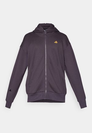 Sudadera morada con cremallera hecha de tejido suave, con una gran capucha, bolsillos frontales y un logo bordado en el pecho y la manga.