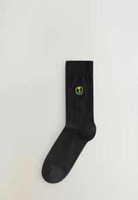 Calzini neri in cotone con risvolto a costine, caratterizzati da un piccolo logo di un trofeo verde e giallo circondato da foglie di alloro sul lato esterno.