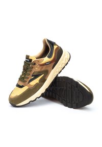 Zapatillas deportivas marrones y amarillas con una parte superior de material mixto de ante y malla, que presentan acentos en negro y una suela de goma texturizada.