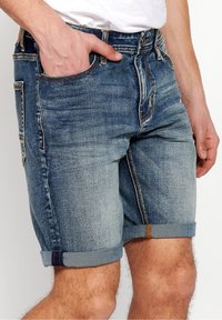Denim shorts in faded blue, featuring a classic five-pocket design, rolled cuffs, and contrasting stitching details.