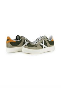 Sneaker in camoscio verde e beige con accenti bianchi, dotate di una parte superiore texturizzata, punta arrotondata e linguetta arancione sul tallone. Suola in gomma bianca spessa.