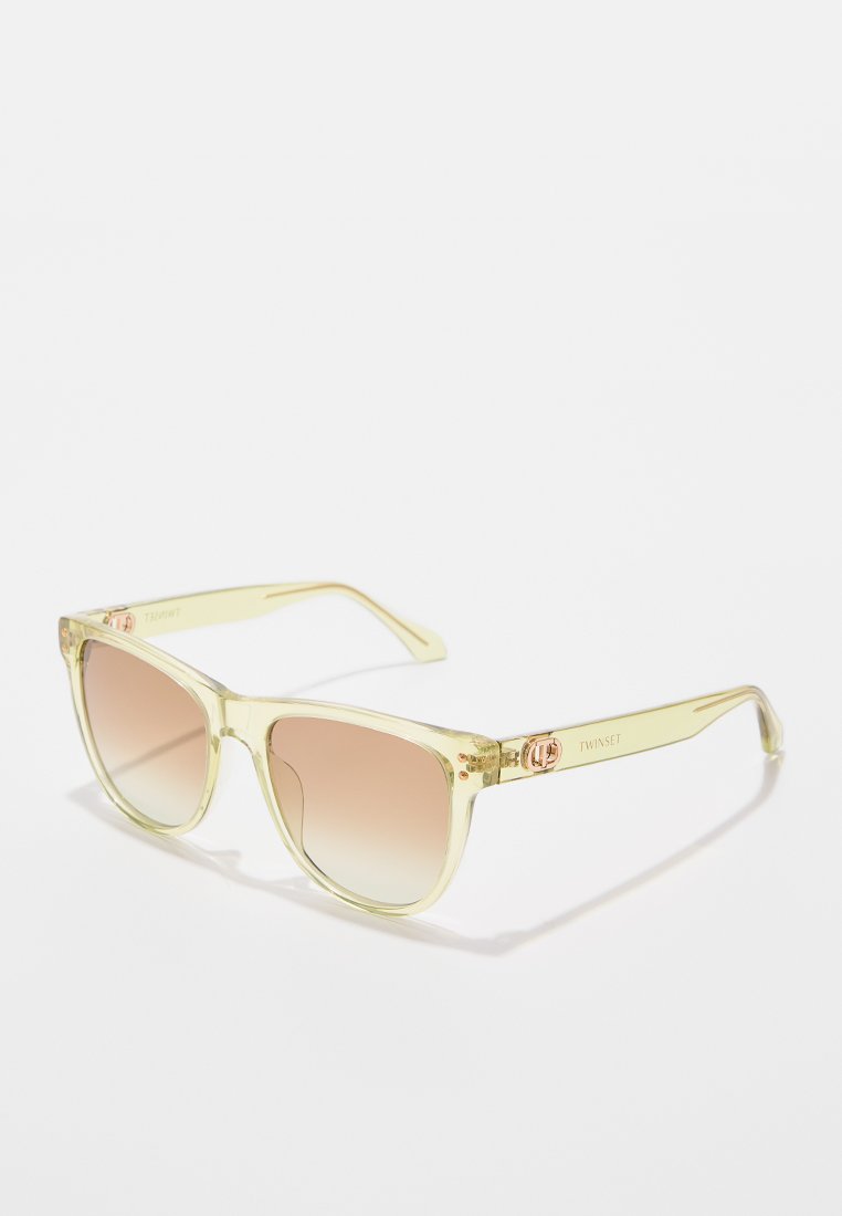 Translucent pale yellow sunglasses with a squared shape, gradient brown lenses, and rose gold logo accent on the temples.