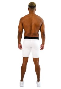 Shorts bianchi con una vita nera, realizzati in materiale elastico, si adattano perfettamente al corpo, mostrando una texture liscia e un design sartoriale.