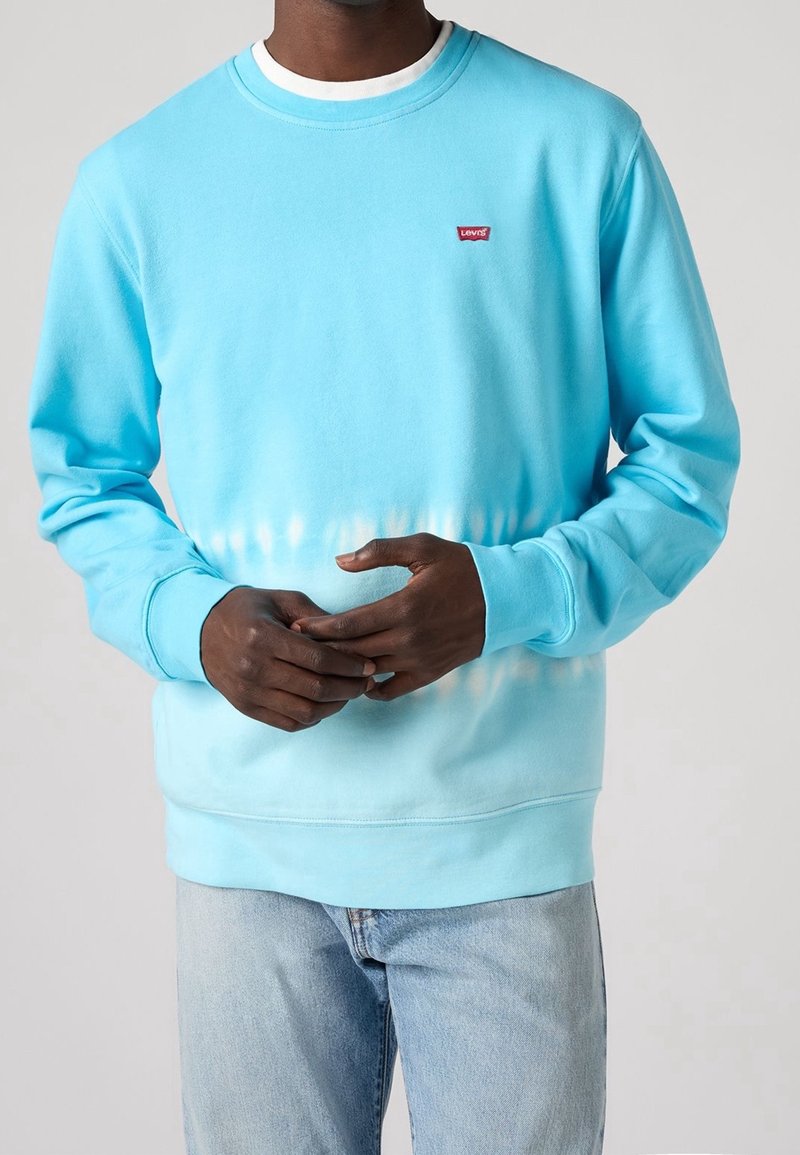 Sudadera azul con un degradado y un pequeño logo rojo de Levi's en el pecho. Material de algodón, cuello redondo, mangas largas, ajuste informal.