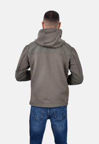 Giacca con cappuccio da uomo in verde oliva, caratterizzata da una texture liscia, orlo a coste e pannelli a contrasto su spalle e maniche.