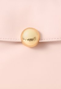 Rózsaszín bőrtáska lekerekített, aranyszínű patentzárral, amelyen kiemelt márkajelzés található. Sima felület, varrott részletekkel a szélén.