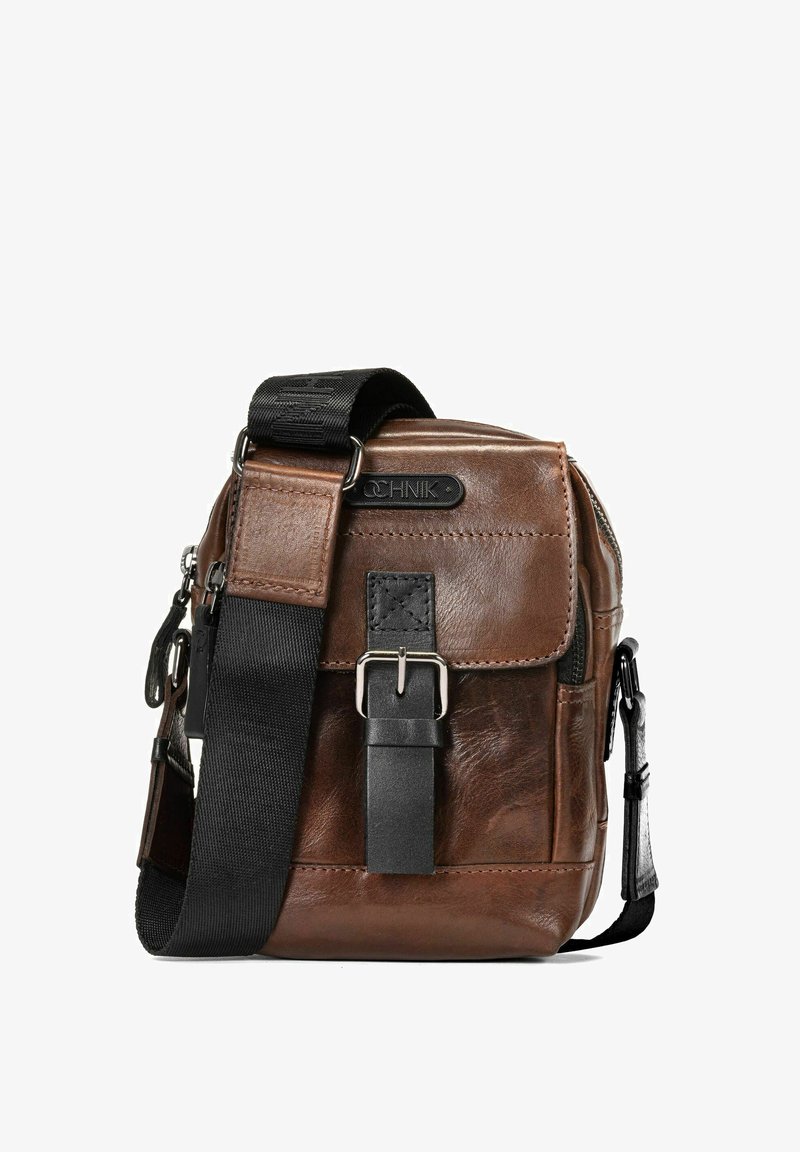 Brązowa skórzana torba na ramię z teksturowanym wykończeniem, regulowanym czarnym paskiem z tkaniny, srebrnymi detalami i zapięciem na klamrę z przodu.
