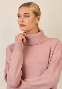 Rosa-pinkfarbener Rollkragenpullover mit gerippten Bündchen und einem lockeren Schnitt. Weiche Textur, leichtes Material, verfügt über einen hohen Kragen für zusätzliche Wärme.