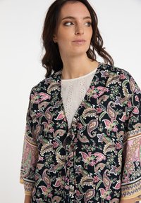 Fekete paisley kimono rózsaszín, zöld és krémszínű virágmintákkal. Háromnegyedes ujjú, kötővel záródik, és könnyű anyagból készült.