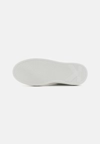 Bílá gumová podrážka boty s texturovaným vlnitým vzorem a logem. Plný design, zaoblené hrany a minimalizované detaily vytvářejí elegantní vzhled.