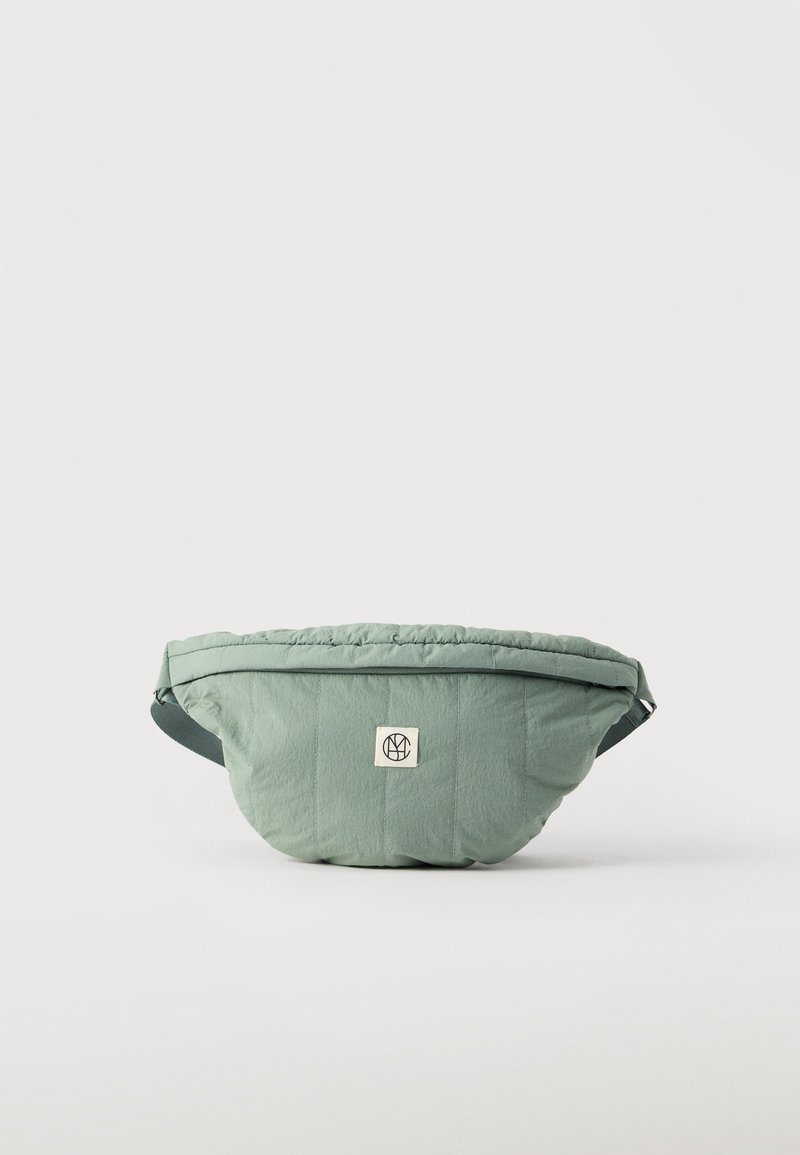 Πράσινη υφασμάτινη τσάντα μέσης με ραμμένο σχέδιο, ρυθμιζόμενο ιμάντα και μπροστινό λογότυπο σε απλό λευκό φόντο.