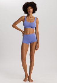 Sujetador deportivo de color púrpura claro y pantalones cortos de talle alto a juego, fabricados con un material elástico de textura suave y costuras mínimas.
