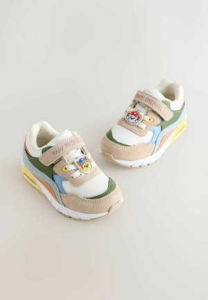 Kindersneakers in beige, groen, blauw en geel met cartoonfiguren versieringen op de banden, tegen een eenvoudige achtergrond.