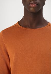 Herren langärmliger, orange gerippter Pullover mit Rundhalsausschnitt, glatter Textur und minimalen Nähten.