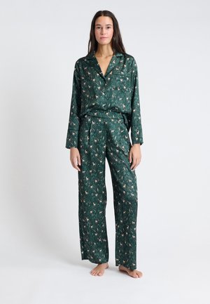 Set di pigiama verde in tessuto leggero con un motivo di cervi su uno sfondo forestale, dotato di colletto a tonache e vita elastica.