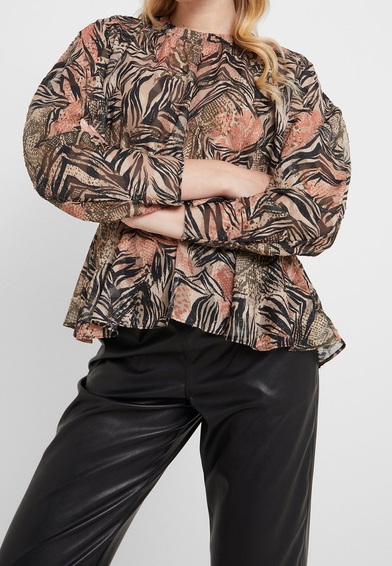 Blouse à manches longues et col rond en tissu transparent à motifs aux tons terreux de brun, orange et noir. Ourlet volanté et épaules froncées.