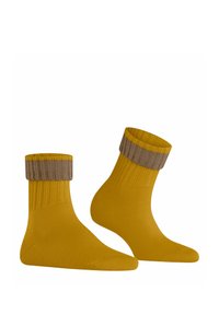 Chaussettes jaunes avec un poignet en marron côtes, présentant une texture lisse et un design ajusté. Le poignet a un motif de rayures contrastées.