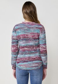 Suéter de punto multicolor con rayas en rosa, azul y blanco, con un acabado texturizado. Mangas largas y detalle de dobladillo redondeado.