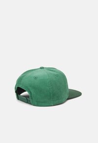 Gorra de pana verde con visera curva a juego, superficie texturizada, cierre ajustable de presión y detalle de botón redondo en la parte superior.