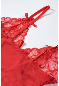 Red lace camisole featuring floral patterns, adjustable satin straps, and a sheer mesh body with scalloped trim detailing.