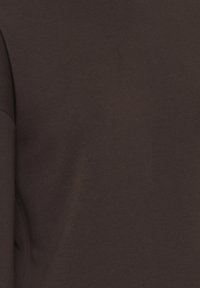 Bruine katoenen t-shirt met een soepele textuur en een fitted ontwerp. Heeft een ronde hals en lange mouwen, met minimale zichtbare stikdetails.