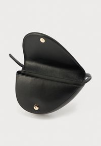 Μαύρη δερμάτινη τσάντα χειρός με καμπυλωτό σχήμα, λεπτομέρειες από χρυσά μεταλλικά στοιχεία και ένα μοναδικό διαμέρισμα. Λεία υφή και μινιμαλιστικός σχεδιασμός.