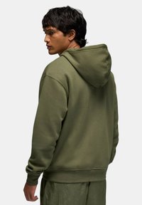 Felpa con cappuccio verde oliva con coulisse, bordi e orlo a coste. Realizzata in tessuto morbido, presenta una vestibilità comoda e una trama liscia.