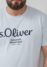 Light blue cotton t-shirt featuring a round neckline, short sleeves, and a prominent black "s.Oliver" logo with text beneath.