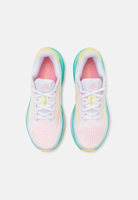Pareja de zapatillas de correr blancas con acentos en rosa, amarillo y turquesa, cordones blancos y marca "Supernova" visible en las plantillas rosas.