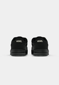 Čierne tenisky Vans s textúrovaným semišovým zvrškom, plochými šnúrkami, polstrovaným golierom a gumovou podrážkou. Branding je v bielej farbe na päte.
