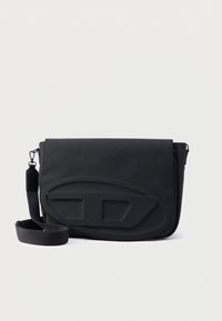 Μαύρο τσαντάκι ταχυμεταφορέα κατασκευασμένο από ανθεκτικό ύφασμα, με λεία επιφάνεια, κλείσιμο με καπάκι και επενδυμένο μπροστινό μέρος με σχηματισμένες λεπτομέρειες.