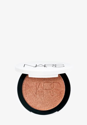 Samengeperste bronzer compact met een witte deksel en een zwarte basis. Het poeder is glanzend brons, met het reliëflogo. Ronde vorm, metalen textuur.