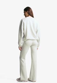 Grijze sweatshirt en bijpassende flared broek van zachte stof, met een relaxte pasvorm en minimale stikdetails.