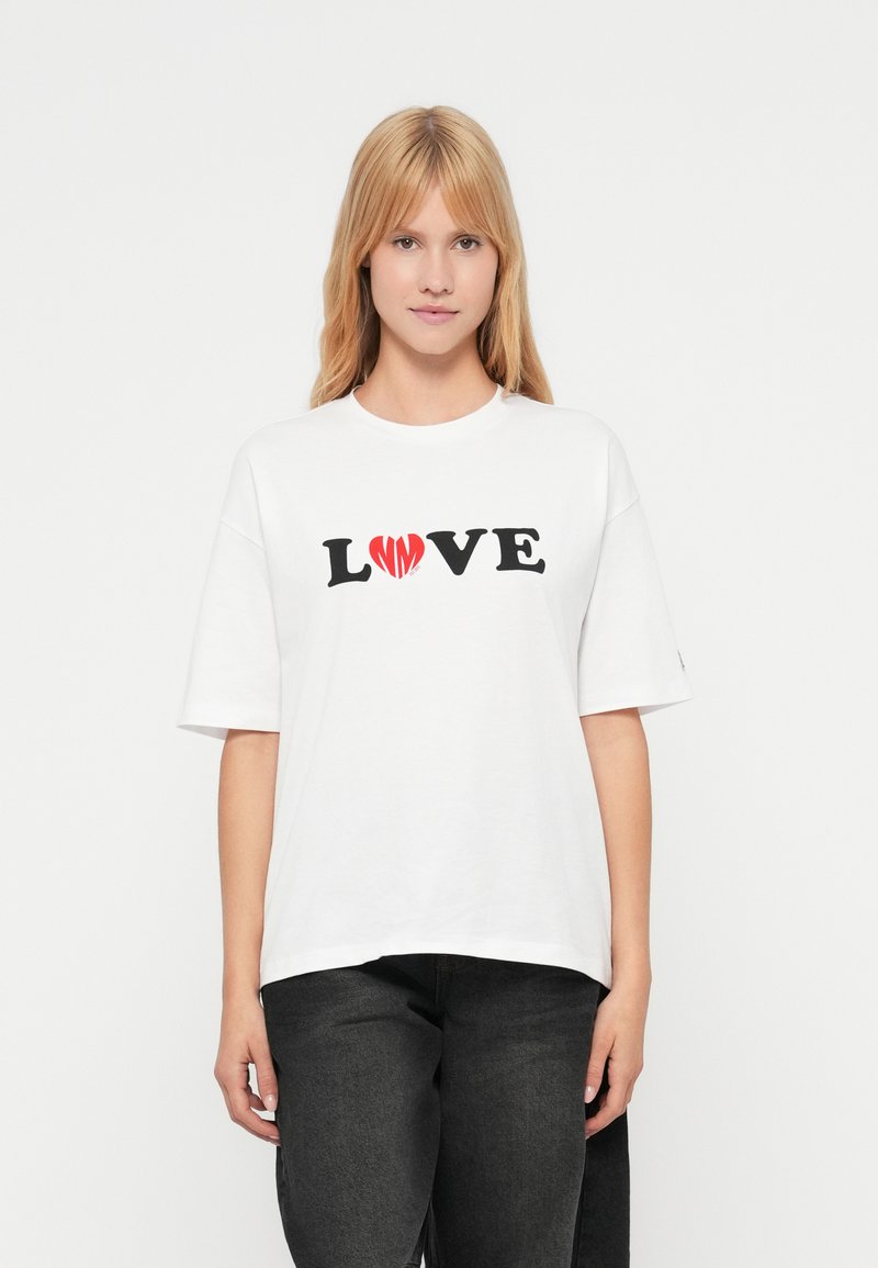 Λευκό βαμβακερό μπλουζάκι με κοντά μανίκια, στο οποίο αναγράφεται "LOVE" με μαύρα γράμματα και διακοσμείται με μια κόκκινη καρδιά. Κανονική εφαρμογή, σχέδιο με στρογγυλή λαιμόκοψη.