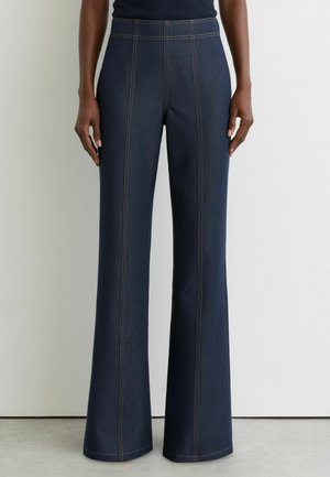Mørkeblå denim flarebukser med kontrastsyninger og høj talje, der har en glat tekstur og brede benåbninger.