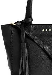 Coin de sac en cuir noir texturé avec une sangle, un détail de franges et trois petits clous métalliques sur le côté visible.