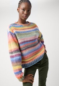 Multikleurige gebreide trui met brede horizontale strepen in pastelkleuren. Ronde halslijn met lange mouwen en ribgebreide boorden.