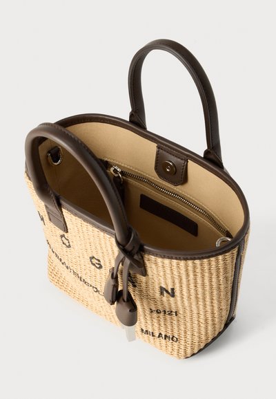Πλεκτή τσάντα από άχυρο με καφέ δερμάτινες λαβές και διακοσμητικά στοιχεία. Διαθέτει μπεζ εσωτερικό, τσέπη με φερμουάρ και τυπωμένο κείμενο στο εξωτερικό μέρος.
