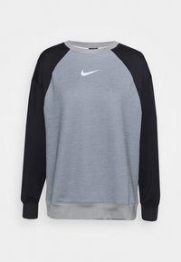 Grå sweatshirt med svarta raglanärmar. Har rund hals, ribbade muddar och en vit Nike-logotyp på bröstet. Mjuk textur.
