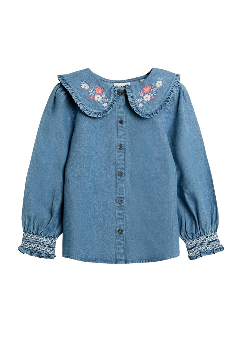 Camicia di denim azzurro chiaro con un ampio colletto volant, ricami floreali e chiusura frontale con bottoni. Maniche a sbuffo con polsini arricciati.