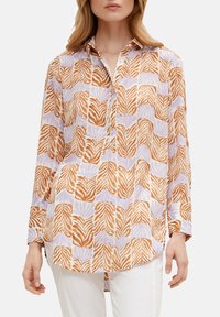 Blusa a maniche lunghe con un design a motivi caratterizzato da foglie arancioni e viola su uno sfondo chiaro, realizzata in tessuto leggero. Dettagli con bottoni visibili.